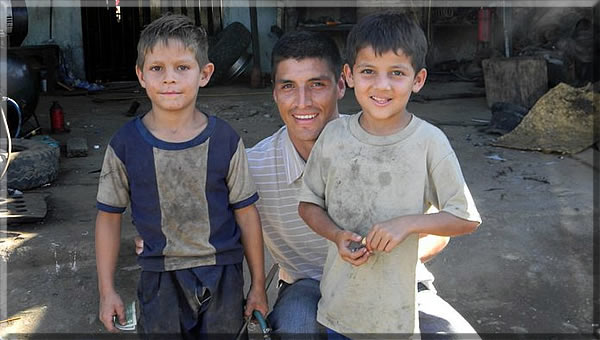 Vinicio with 2 young boys after teaching them how to change a tire.