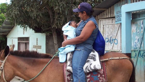 A mother carries her baby on a horse in Ecuador.