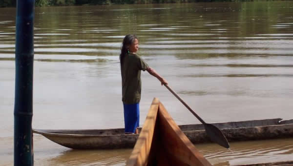 A woman travels down the river in a canoe.